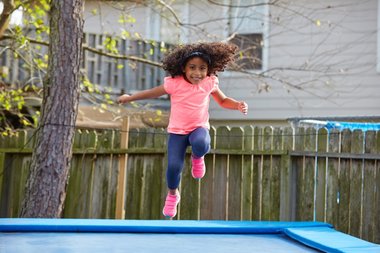 Pige der hopper på en firkantet trampolin